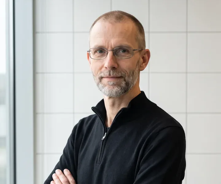 Indrek Lehtla mustas pulloveris, käed rinnal risti, seljataga valge plaatsein ja vasakul aken, plaadiliim segatakse ühe kotitäie kaupa, et segu ei hakkaks ämbris enne kasutamist tahenema.